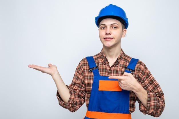 Heureux de faire semblant de tenir et de pointer vers quelque chose de jeune constructeur masculin en uniforme