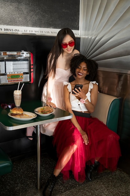 Photo gratuite heureux les femmes assises à table plein coup