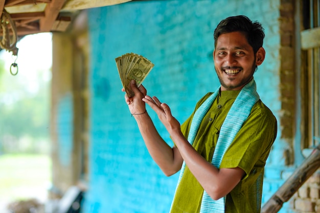 Heureux fermier indien montrant de l'argent à la maison.