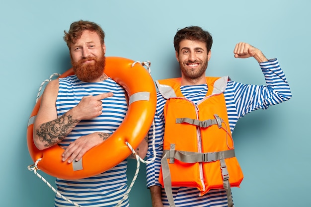 Heureux et fier nageur lève le bras et montre ses muscles, prêt à sauver la vie des gens sur l'eau