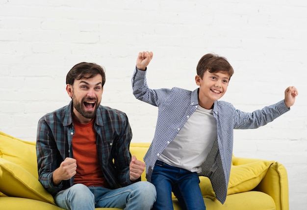 Photo gratuite heureux fils et père assis sur un canapé