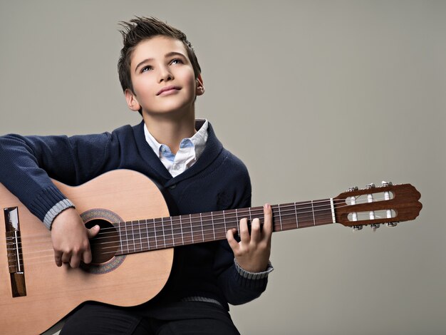 Heureux garçon jouant avec plaisir à la guitare acoustique.