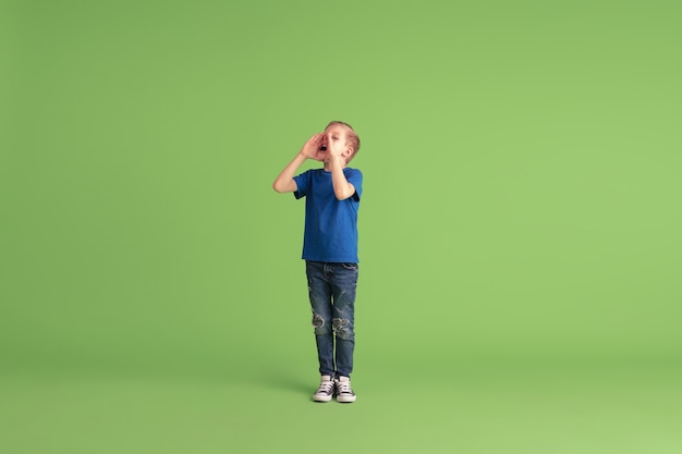 Photo gratuite heureux garçon jouant et s'amusant sur les émotions du mur vert