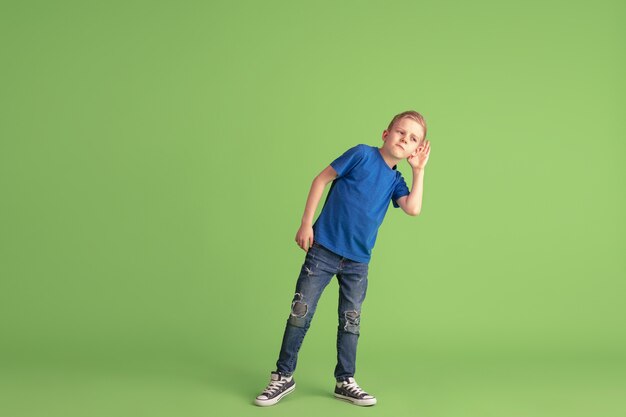 Heureux garçon jouant et s'amusant sur le mur vert du studio