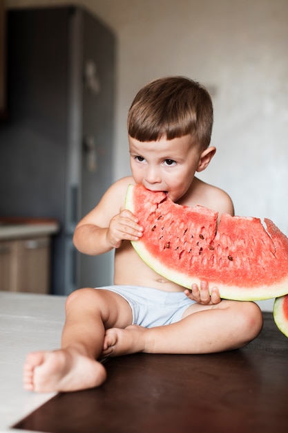 Heureux Garçon Mangeant Une Tranche Géante De Melon D'eau