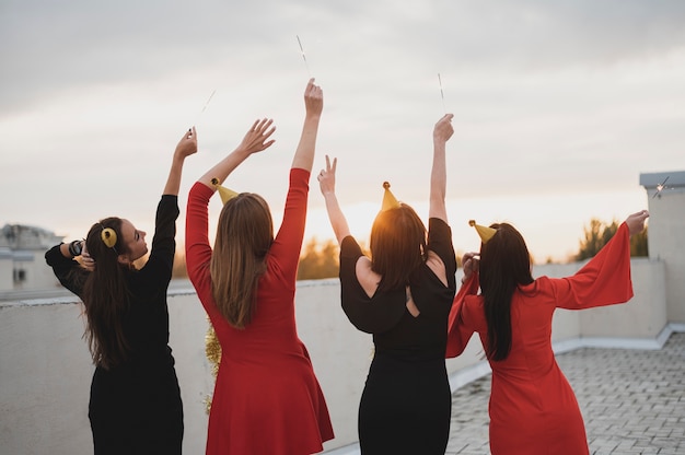 Heureux groupe de femmes admirant le coucher de soleil sur le toit