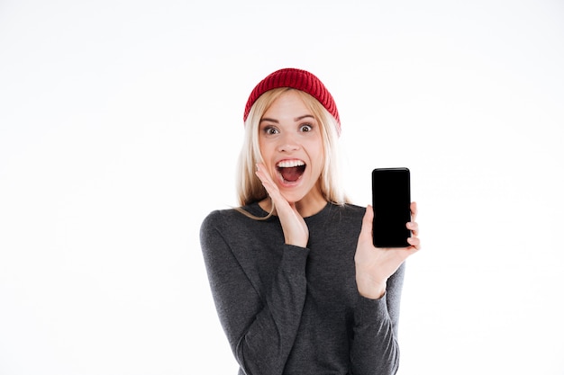 Heureux heureux jeune femme décontractée montrant un téléphone mobile à écran blanc