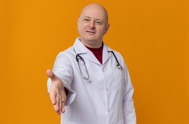 Heureux homme adulte en uniforme de médecin avec stéthoscope tendant la main