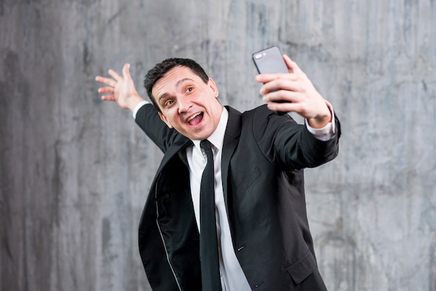 Heureux homme d&#39;affaires, levant la main et prenant selfie