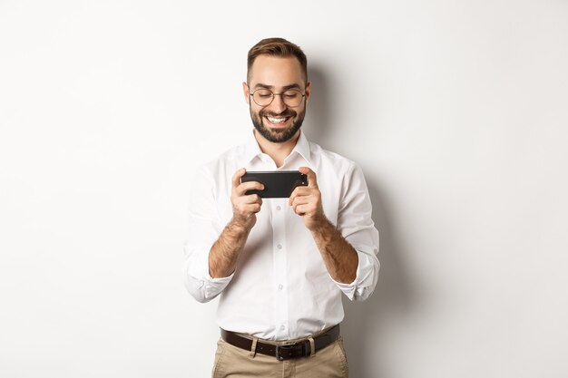 Heureux homme d'affaires, regarder la vidéo sur téléphone mobile, debout.