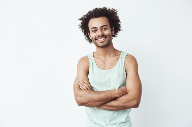 Heureux homme africain souriant posant avec les bras croisés.