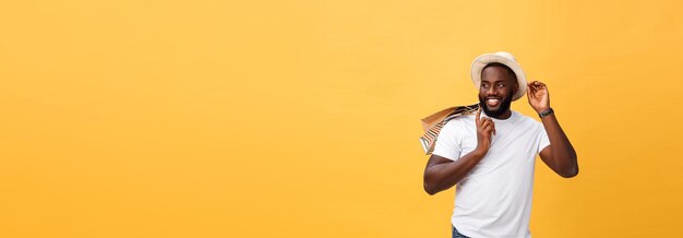 Heureux homme afro-américain tenant des sacs à provisions sur le concept de vacances de fond jaune