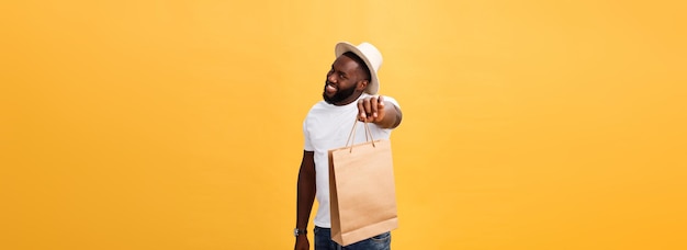 Photo gratuite heureux homme afro-américain tenant des sacs à provisions sur le concept de vacances de fond jaune