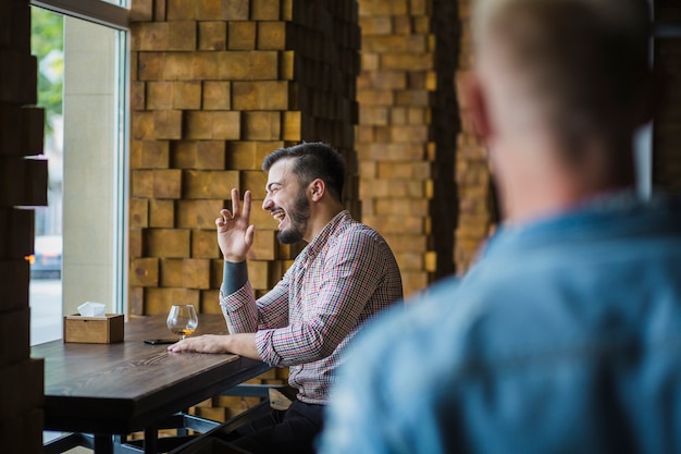 Photo gratuite heureux homme assis au restaurant en appréciant des boissons