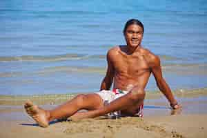 Photo gratuite heureux l'homme assis dans le sable