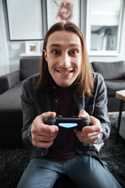 Heureux homme assis à la maison à l'intérieur jouer à des jeux