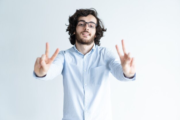 Heureux homme aux cheveux noirs montrant deux signes de victoire