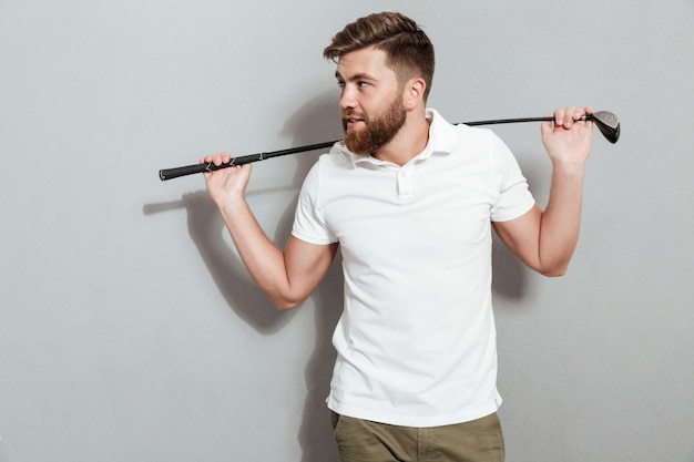 Heureux homme barbu posant avec club et en détournant les yeux