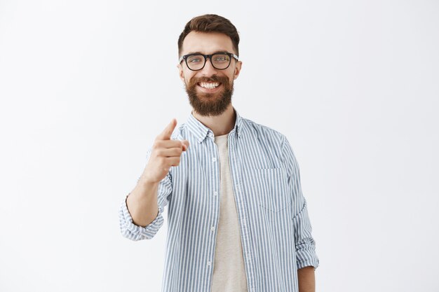 Heureux homme barbu posant contre le mur blanc