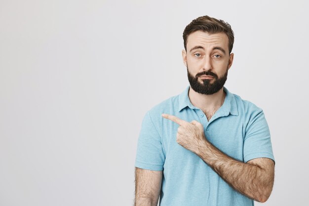 Heureux homme caucasien pointant à gauche impressionné