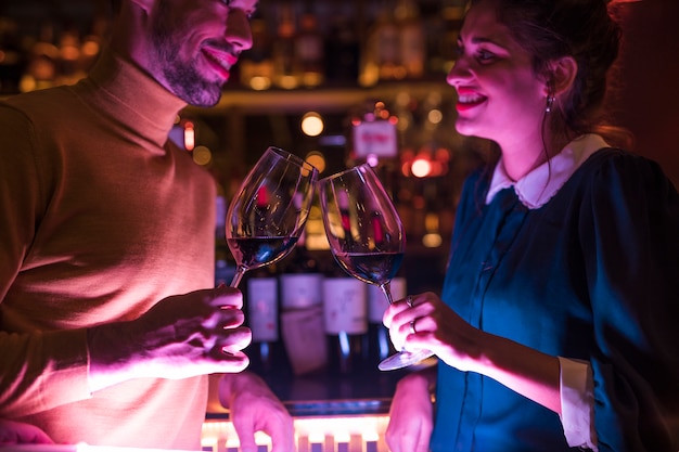 Heureux homme claquant des verres de vin avec une femme joyeuse