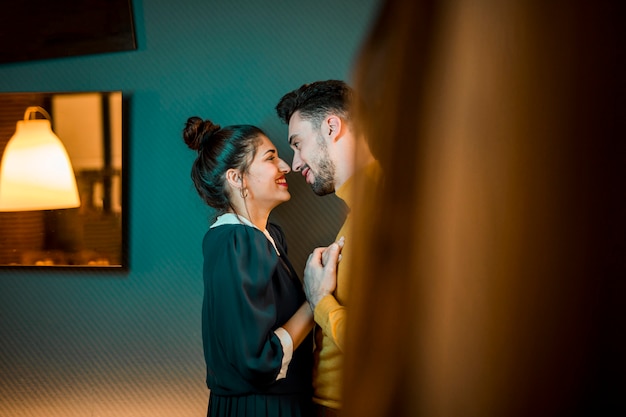 Heureux homme embrassant une femme joyeuse dans la chambre