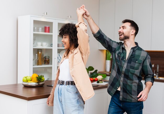 Heureux homme et femme danser dans la cuisine