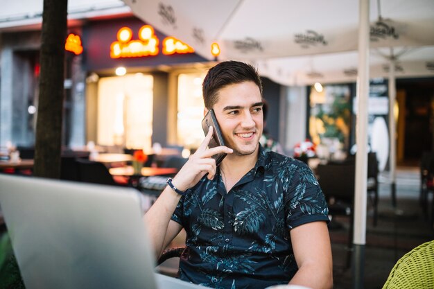 Heureux homme parlant sur smartphone au café