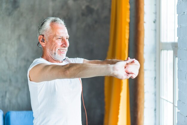 Heureux homme senior qui s&#39;étend de sa main tout en faisant de l&#39;exercice