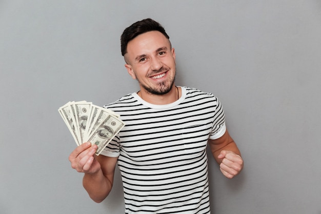Photo gratuite heureux homme en t-shirt tenant de l'argent et regardant la caméra