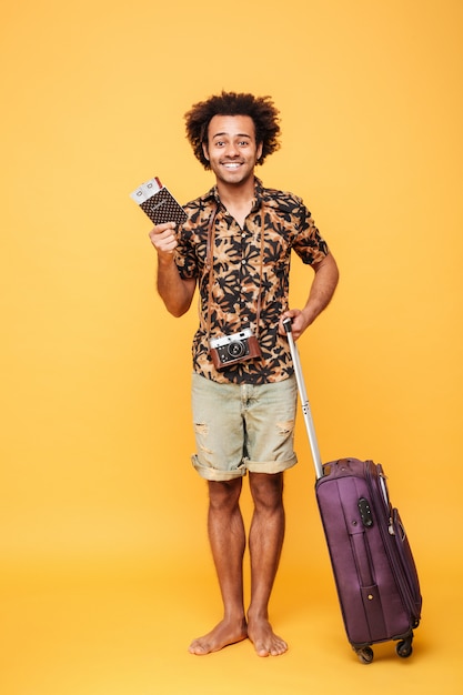 Heureux homme tenant un passeport et une valise.