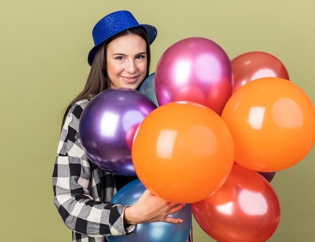 Heureux jeune belle fille portant un chapeau bleu tenant des ballons