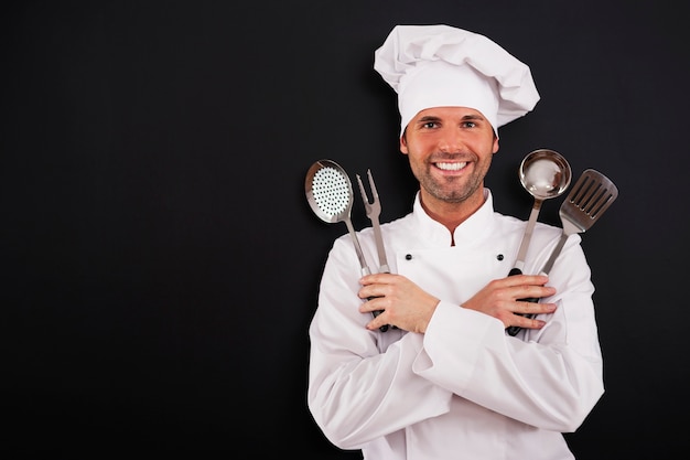 Photo gratuite heureux jeune chef avec équipement de cuisine