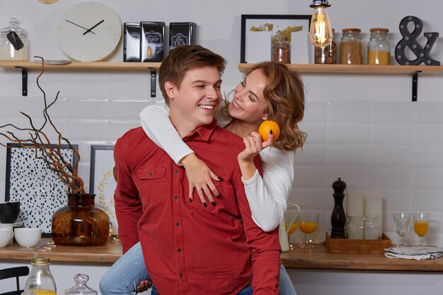 Heureux jeune couple adorable dans la cuisine se serrant les uns les autres. Ils aiment passer du temps ensemble. L'homme tenant sa petite amie