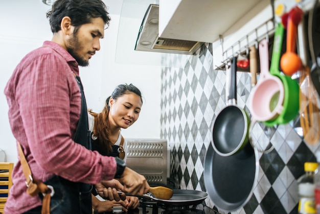 Heureux jeune couple aidant les uns les autres cuisine dans la cuisine à la maison.