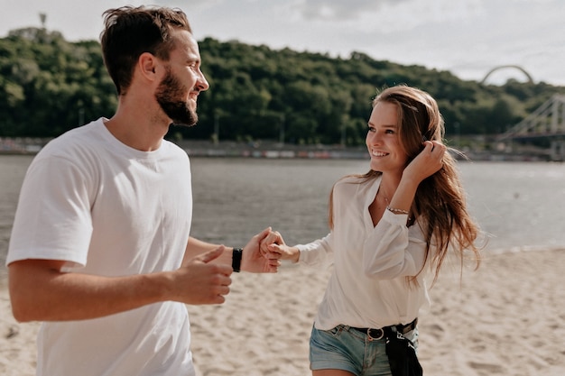 Heureux jeune couple amoureux et souriant tout en couvrant sur la plage près du lac