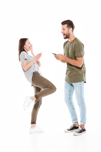 Heureux jeune couple d'amoureux tenant des téléphones.