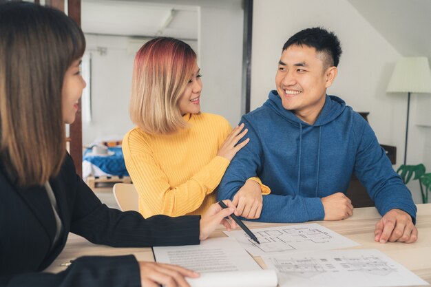 Heureux jeune couple asiatique et agent immobilier