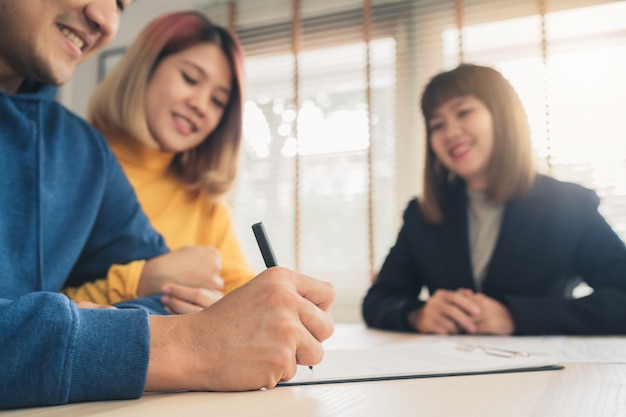 Heureux jeune couple asiatique et agent immobilier