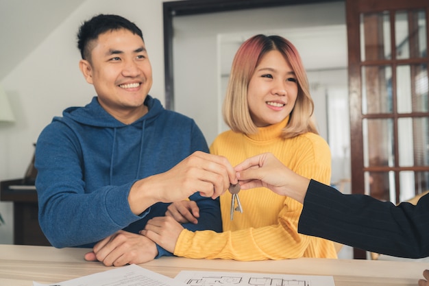 Heureux jeune couple asiatique et agent immobilier