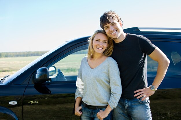 Heureux jeune couple beau debout près de la voiture