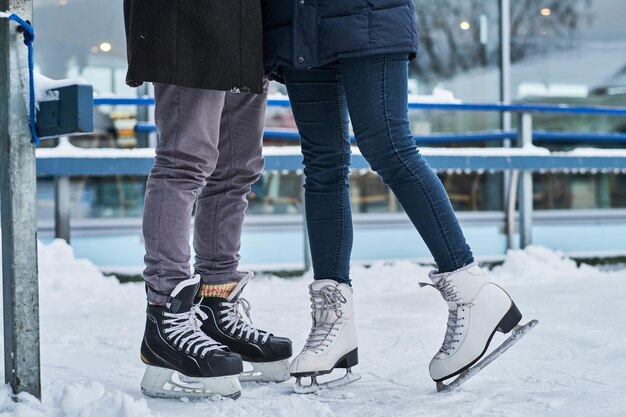 Heureux jeune couple datant de la patinoire, étreignant et profitant de l'hiver
