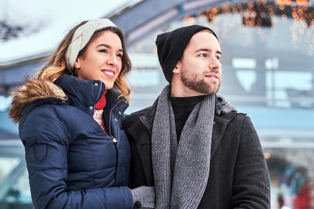 Heureux jeune couple datant de la patinoire, étreignant et profitant de l'hiver