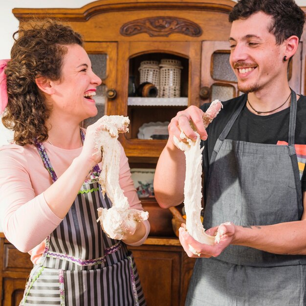 Heureux jeune couple, étirement de la pâte dans leurs mains