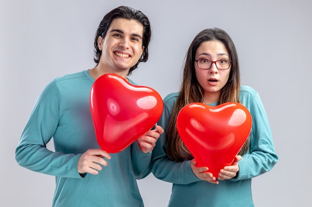 Heureux jeune couple le jour de la Saint-Valentin tenant des ballons coeur isolé sur fond blanc