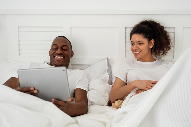 Heureux jeune couple regardant quelque chose sur tablette