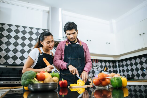 Heureux jeune couple s&#39;entraident couper les légumes préparer pour la cuisson dans la cuisine