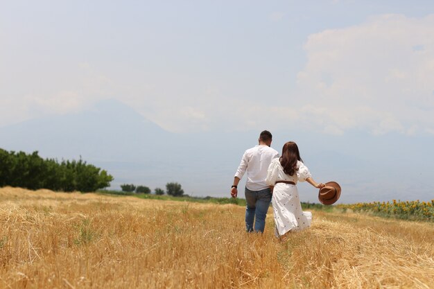 Heureux jeune couple s'exécutant dans un champ d'herbe sèche avec ciel bleu