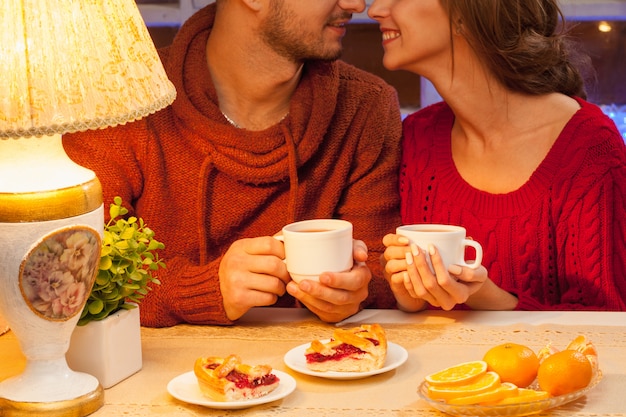 L'heureux jeune couple avec des tasses de thé et des gâteaux.