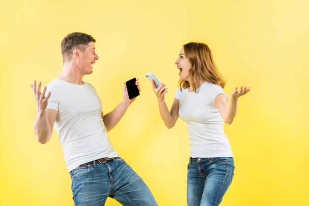 Heureux jeune couple tenant un téléphone portable dans la main en criant de joie